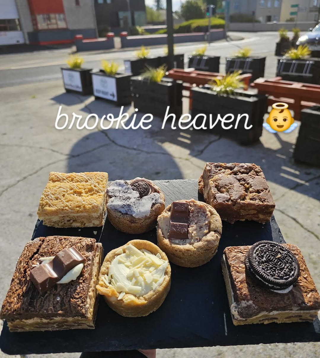 Assortment of brownies and cookie cups on a dark slate board