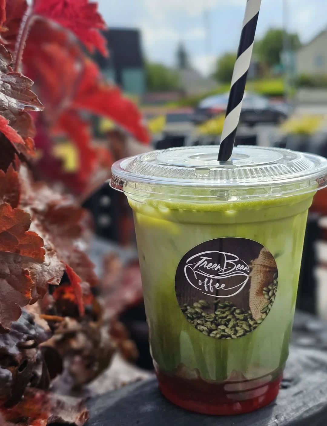 Iced green layered drink with a black and white striped straw