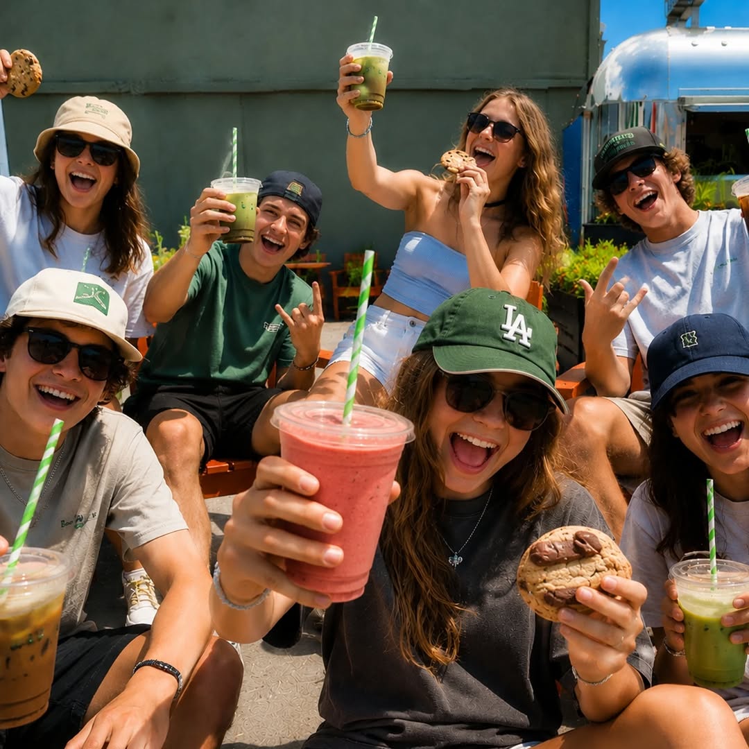 Group of young people smiling and holding coffee and cookies outdoors