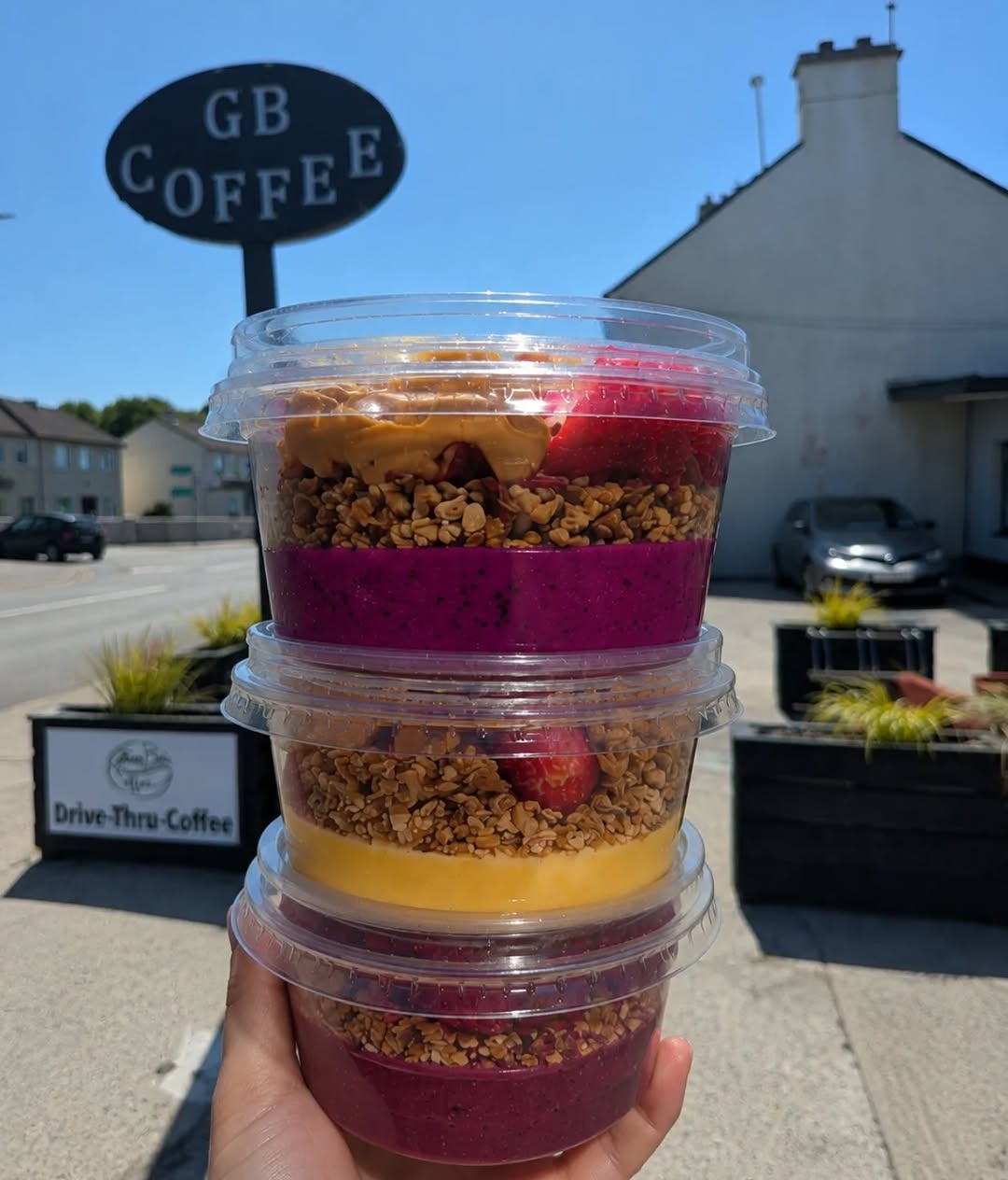 Stack of three layered smoothie bowls held outdoors