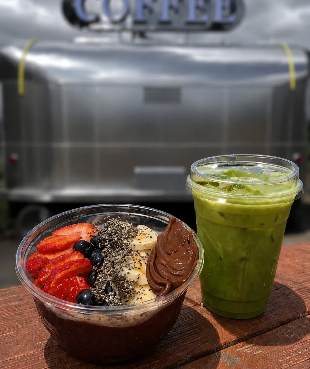 Acai bowl with fruit and peanut butter next to a green iced drink